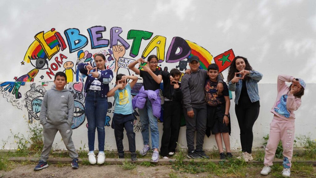 Niños, niñas y adolescentes de Amoverse posan delante de un mural con la palabra Libertad
